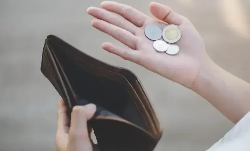 A person counts coins while holding a wallet