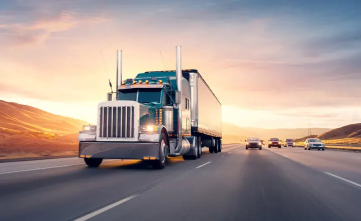 a semi truck driving down a highway at sunset