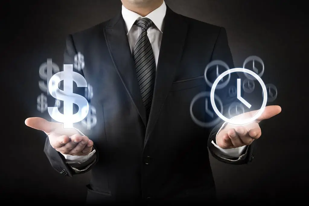A person in a suit holds a floating dolar symbol in one hand and a clock icon in the other.