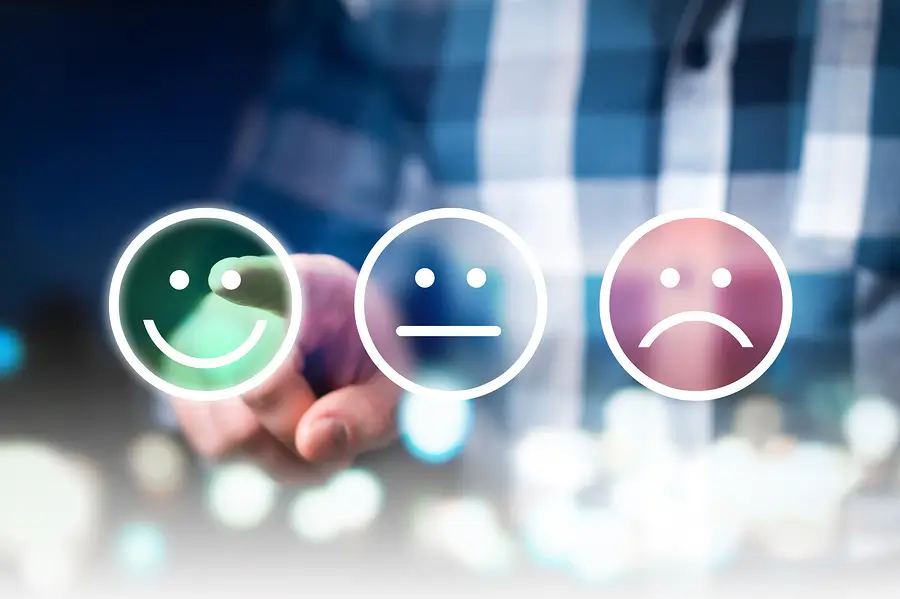 There are three emoticons, happy, poker face, and sad, and in the background is a person pointing at the happy emoji