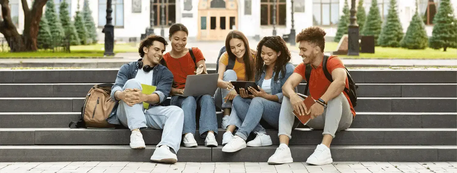 A group of people sitting in stairs possibly located in a college campus.